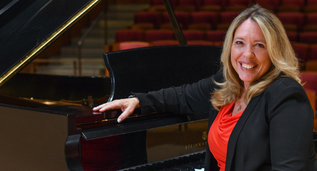 Woman sitting at piano with red shirt and black jacket